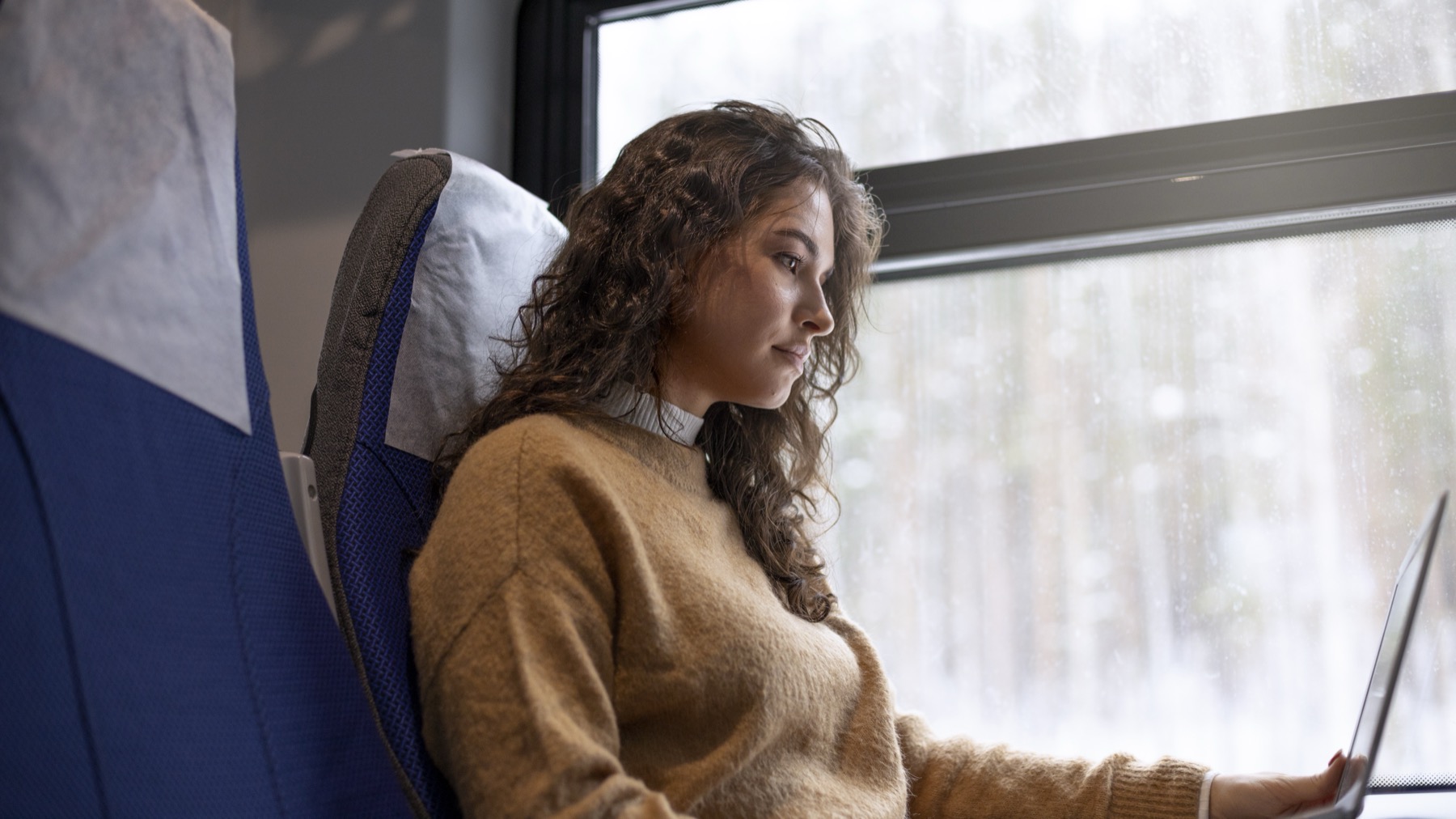 Traveler working on a laptop on a train, illustrating Ubigi prices by country for travel eSIM data plans