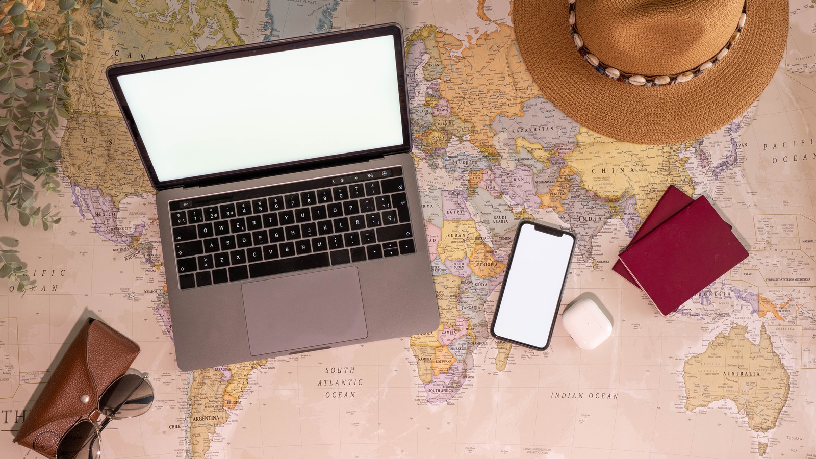 Laptop, passports and a smartphone laid out on a world map, illustrating digital nomad eSIM cost by country